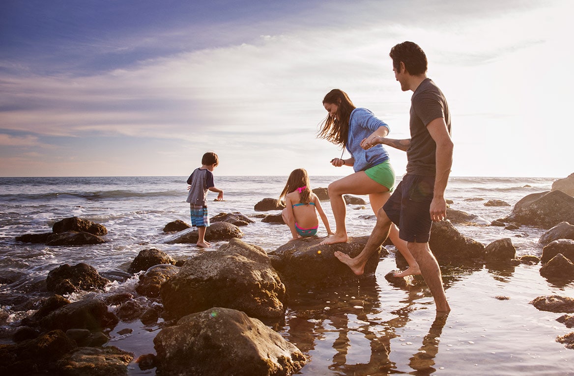 alojamiento-cantabria-playa-familia-padres-ninos-disfrutando-playa-rocas